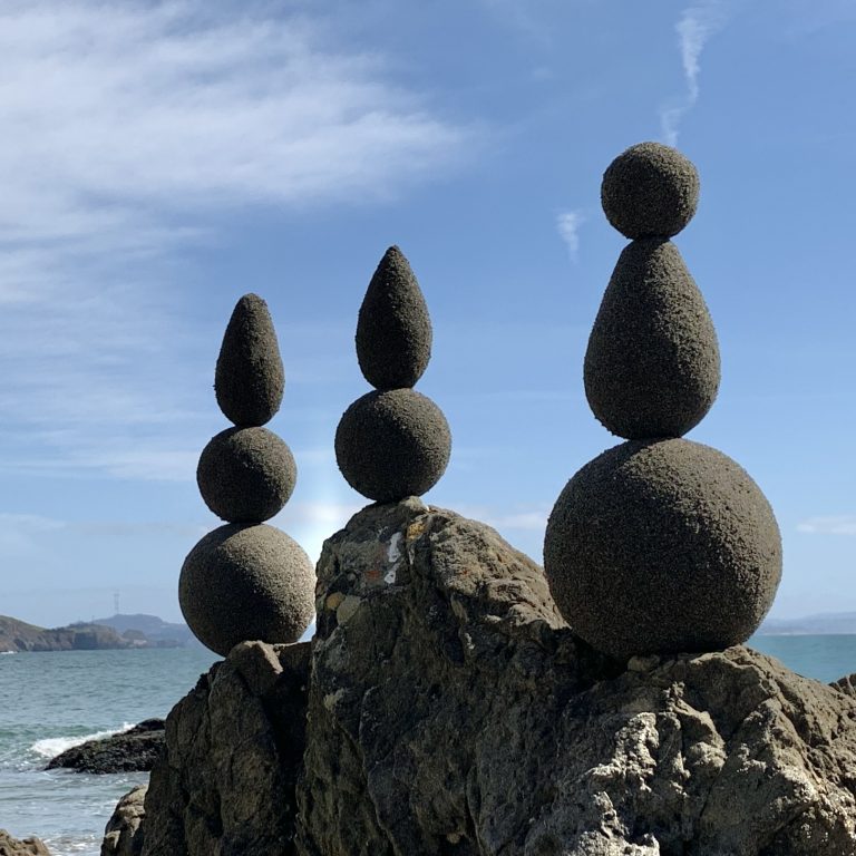 Sand globes stacked on rocks on the beach
